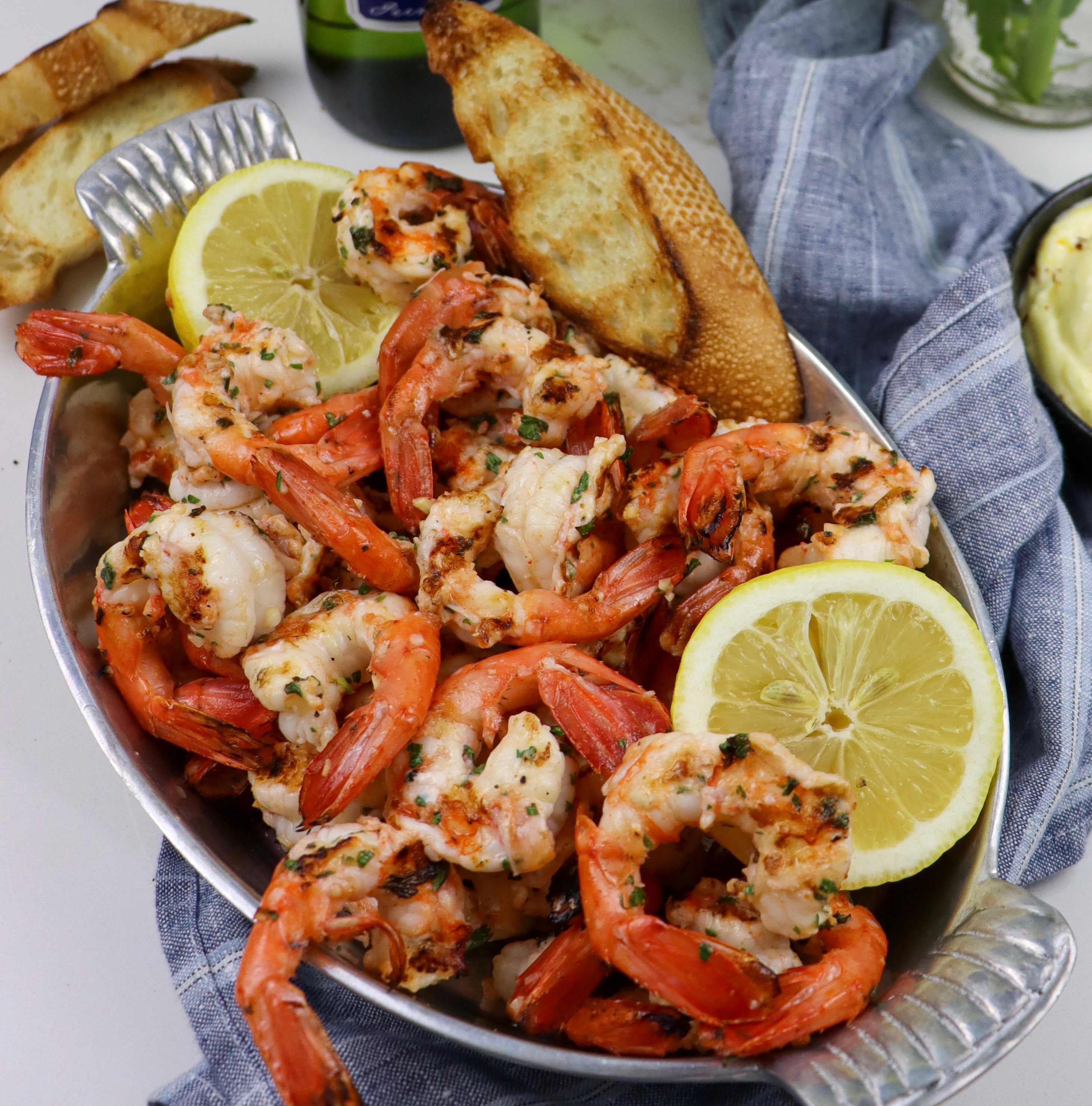 Dish of grilled spot prawns with grilled baguette and lemon wedges