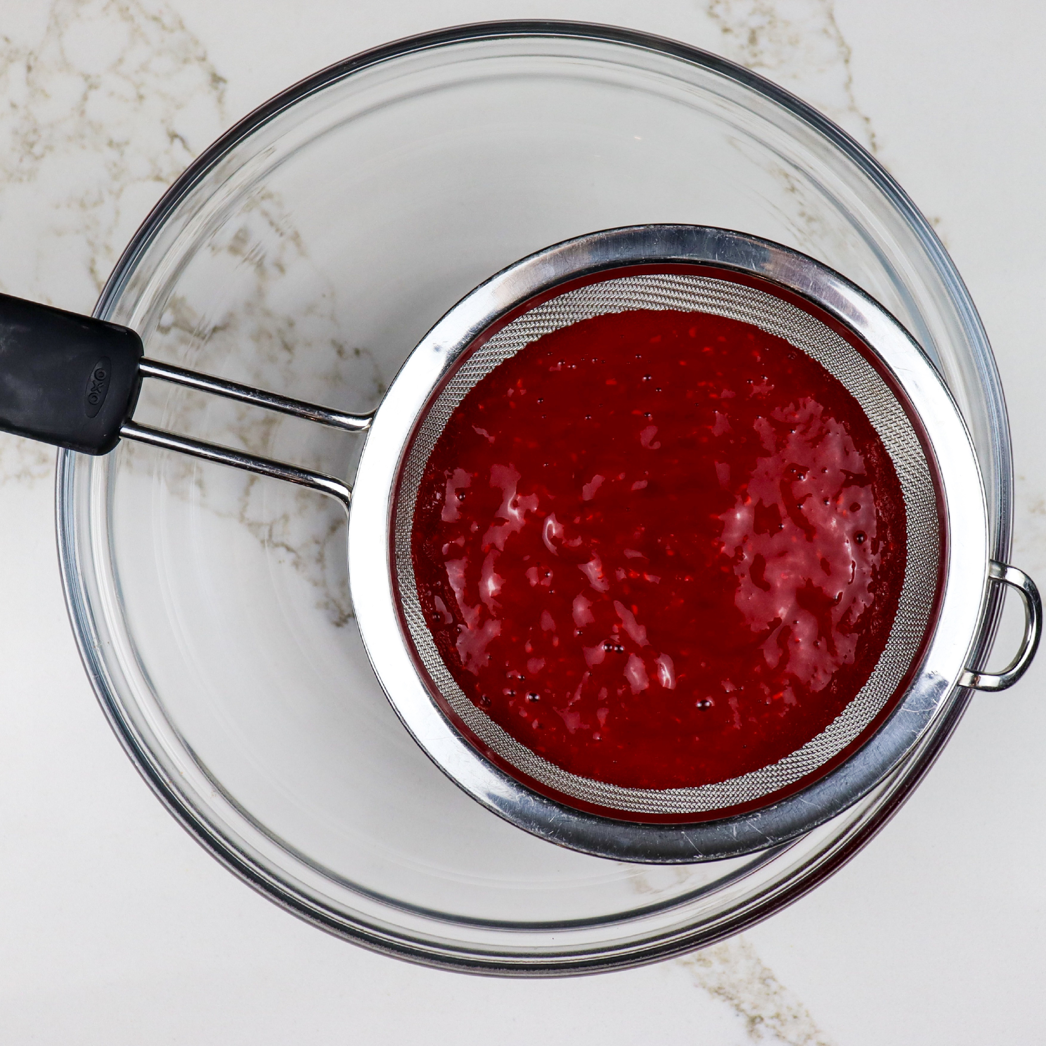 Raspberry jelly purée in a strainer