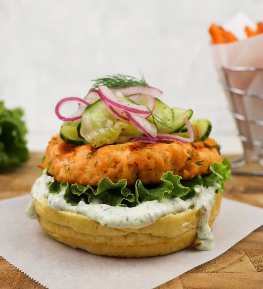 Salmon burger stacked wit toppings with a bun top