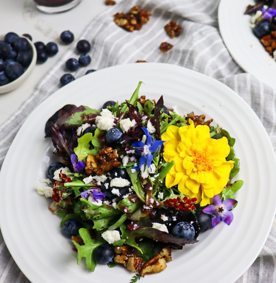 Plate of blueberry salad topped with edible flowers