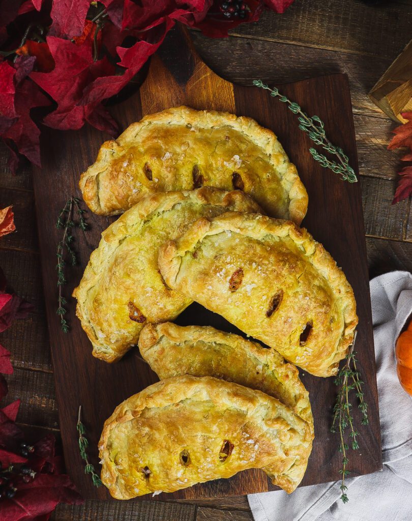 Five pumpkin pasties sitting on a cutting board