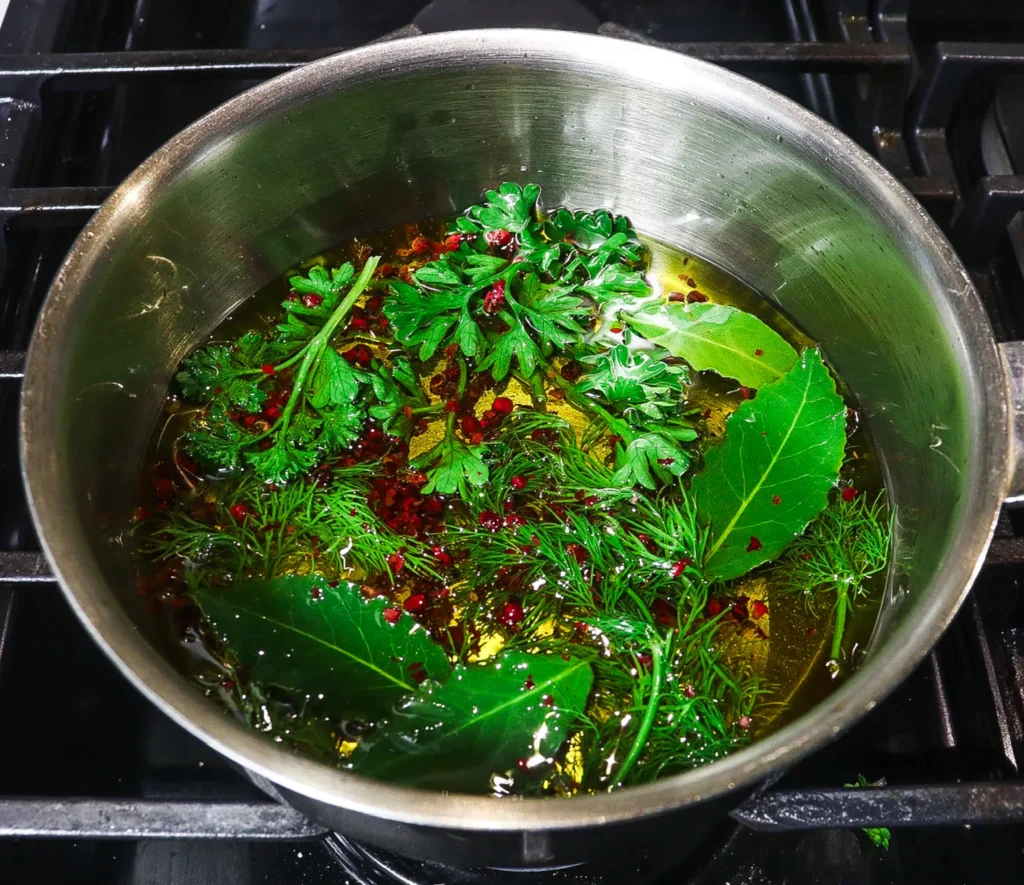  Herbs and peppercorns in a metal bowl infusing oil