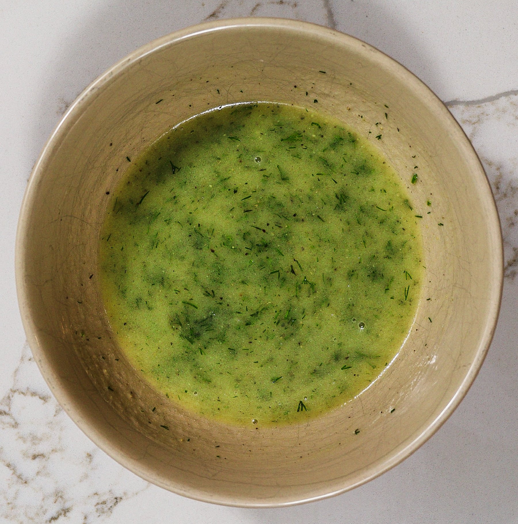 Bowl of whisked dijon mustard vinaigrette with honey, lemon and fresh dill