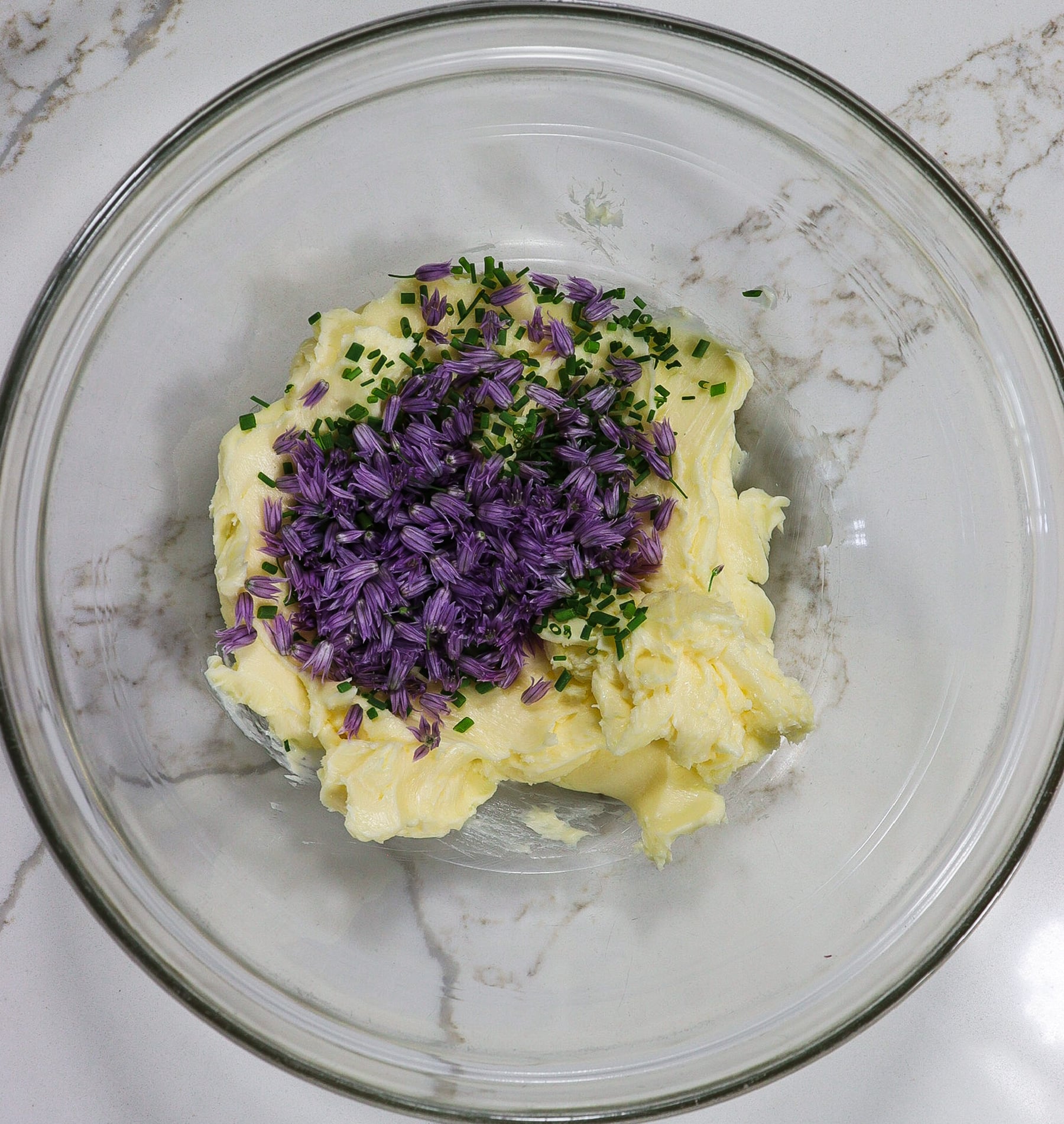 Butter, chives and chive blossoms in a mixing bowl unmixed