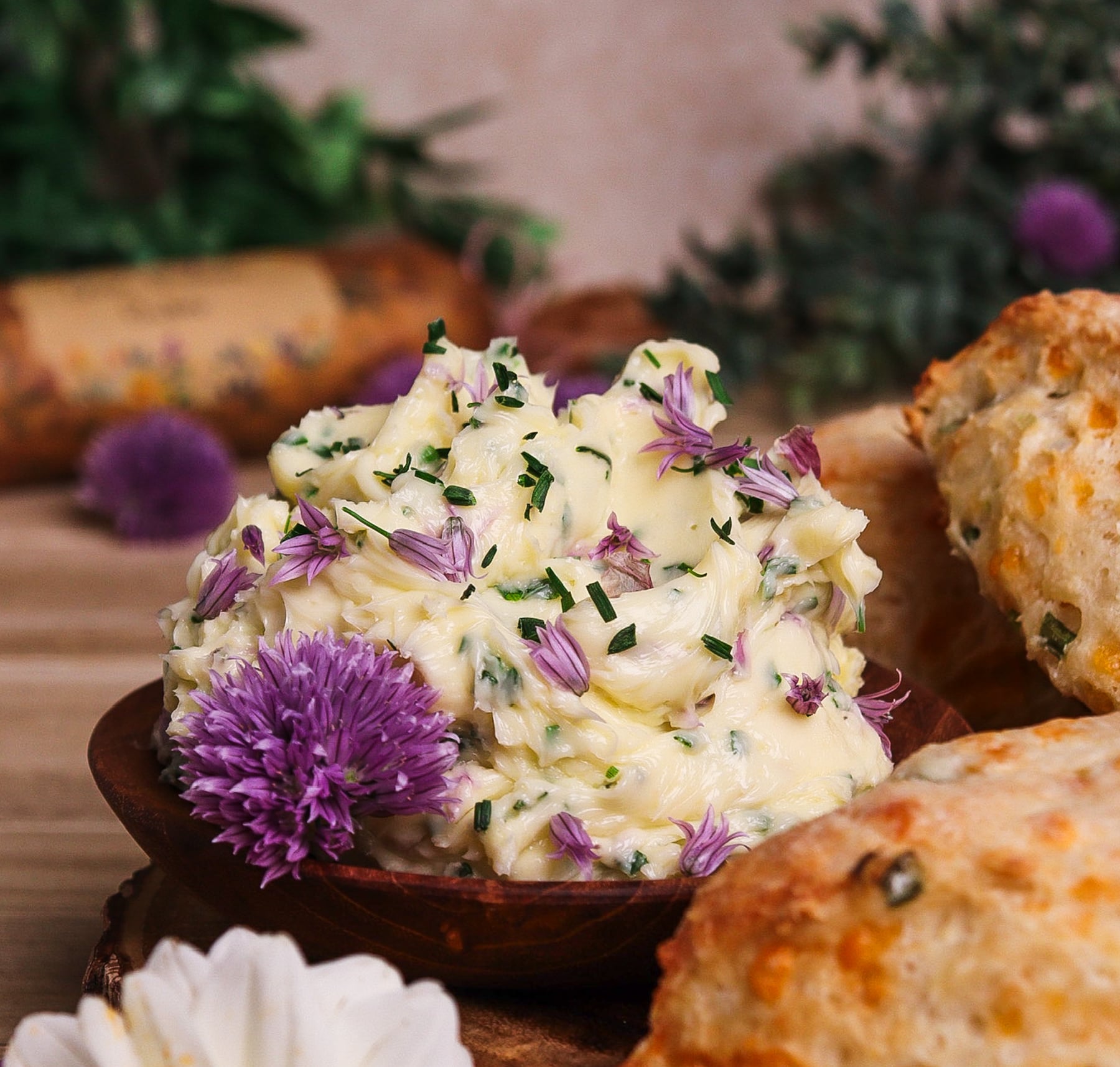 compound butter with chive blossoms and chives in a rustic dissh