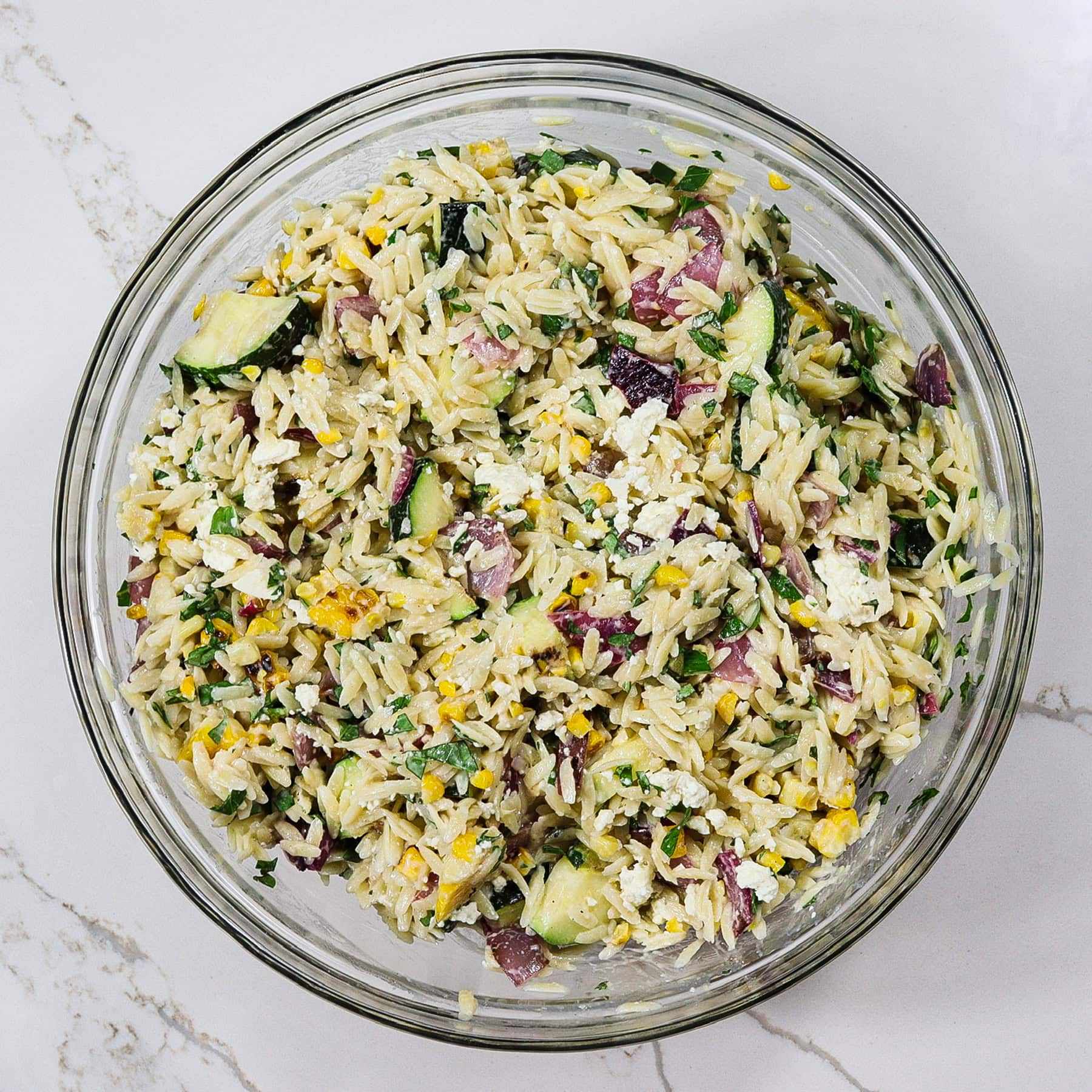 orzo pasta salad with grilled summer vegetables in a mixing bowl