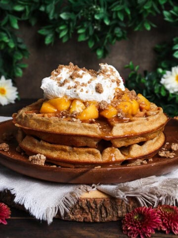 Stack of peach crisp waffles in a rustic floral setting