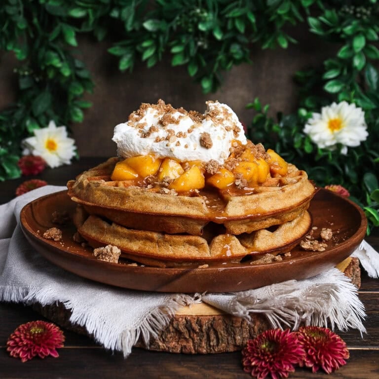 Stack of peach crisp waffles in a rustic floral setting