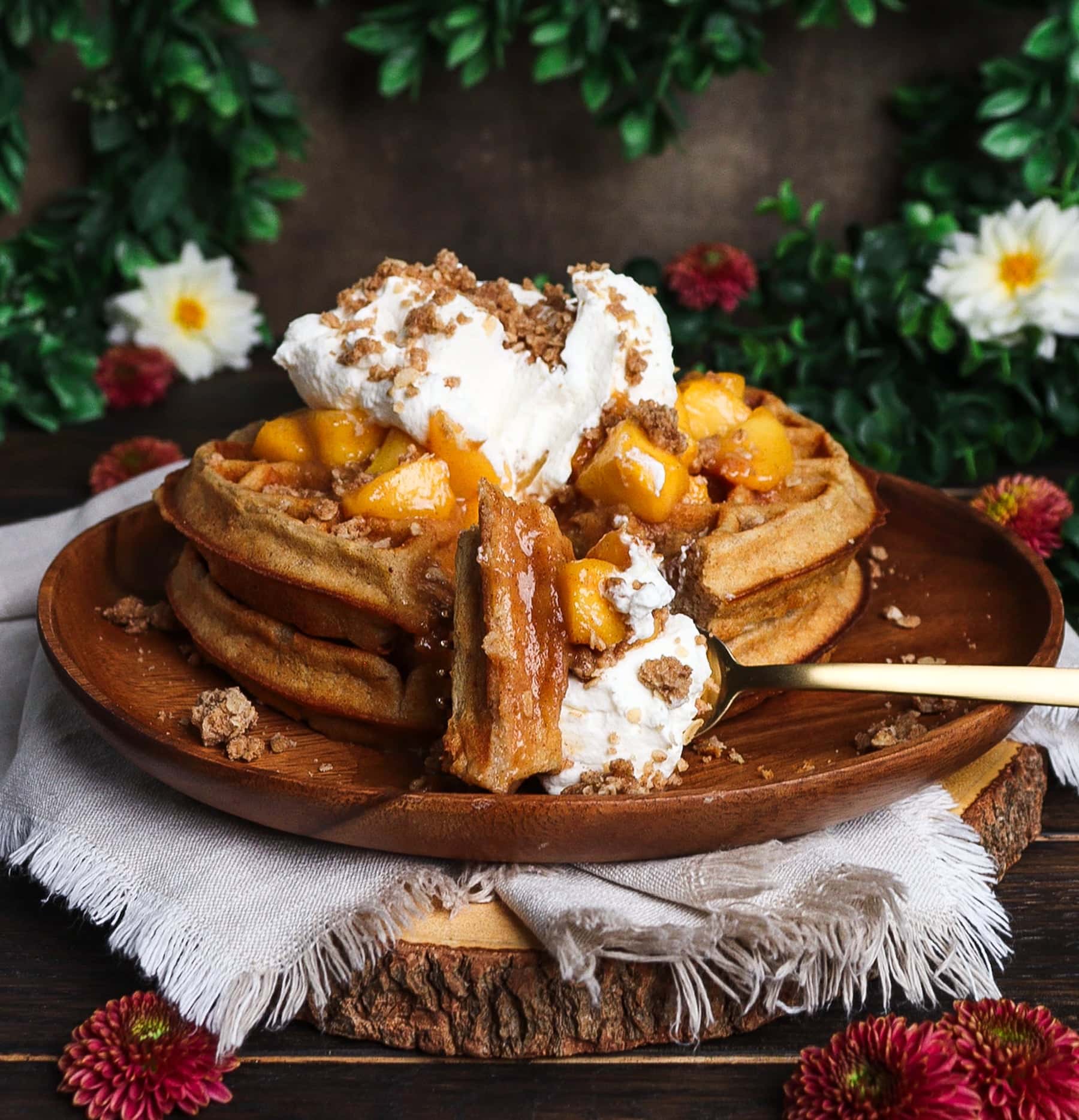 stack of peach crisp waffles on a rustic plate with a fork