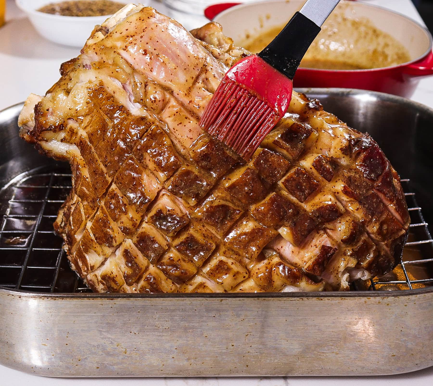 baked ham being glazed with honey mustard beer glaze