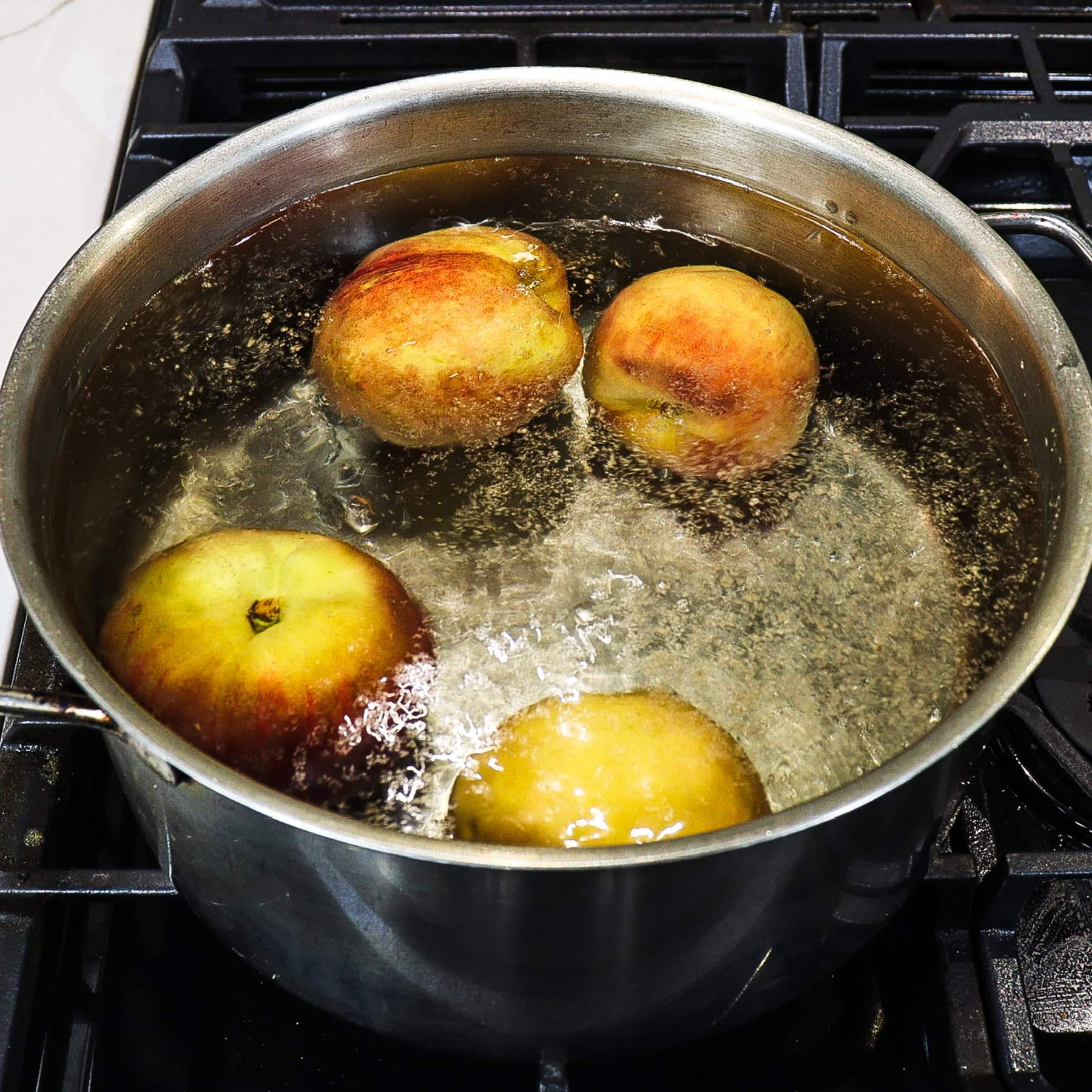 peaches blanching in boiling water on a stovetop