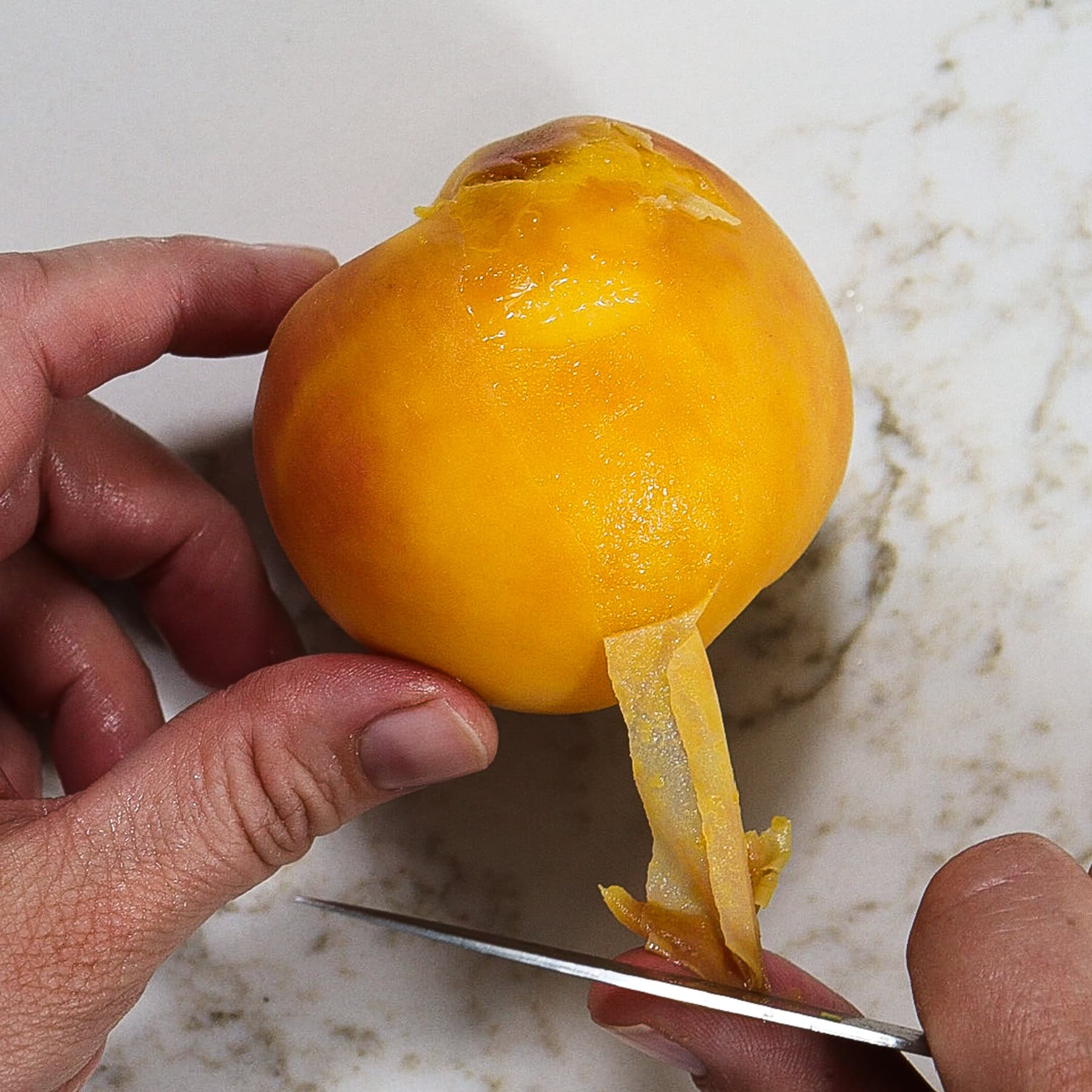 peeling the skin from blanched peaches for jam