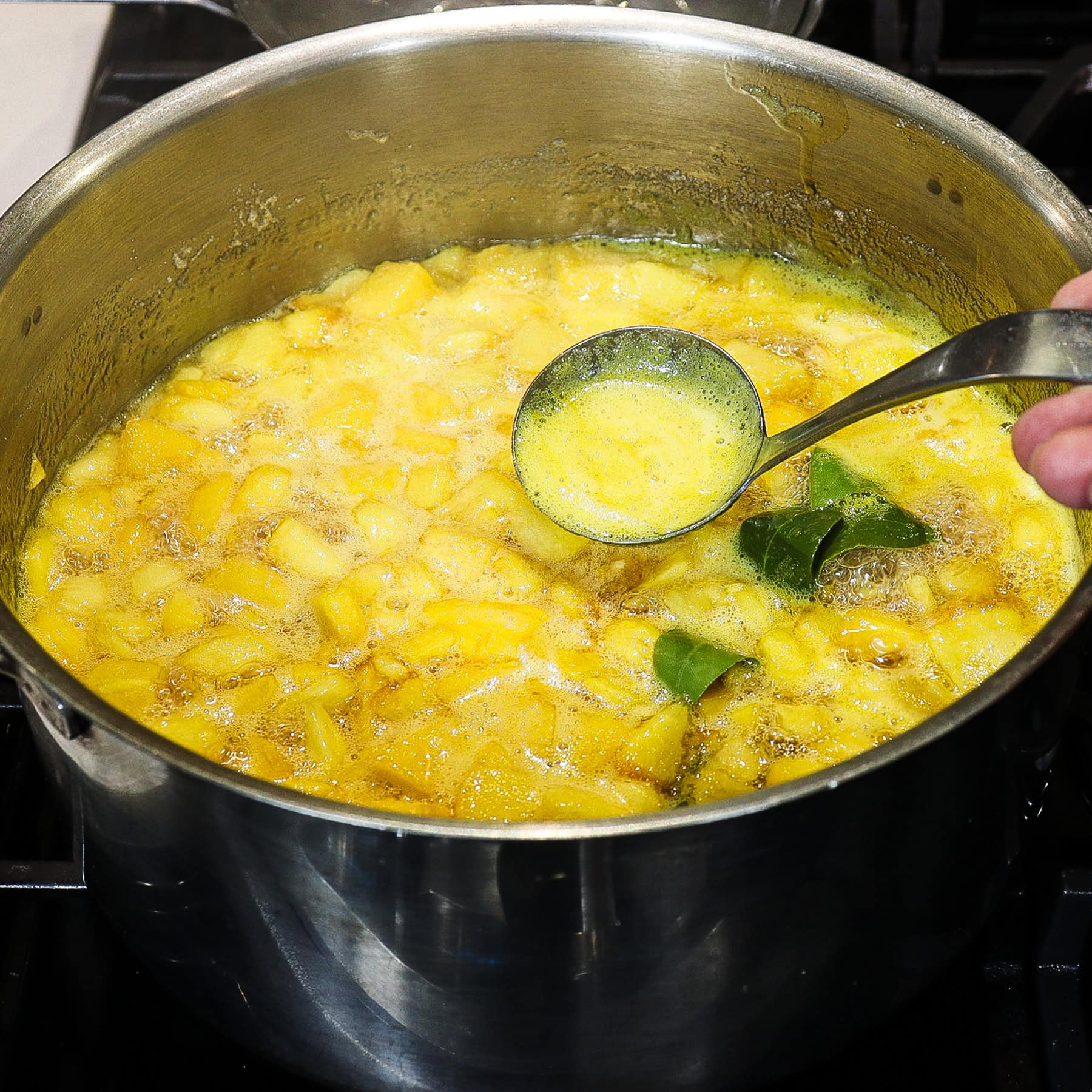 skimming excess foam off of peach jam cooking stovetop