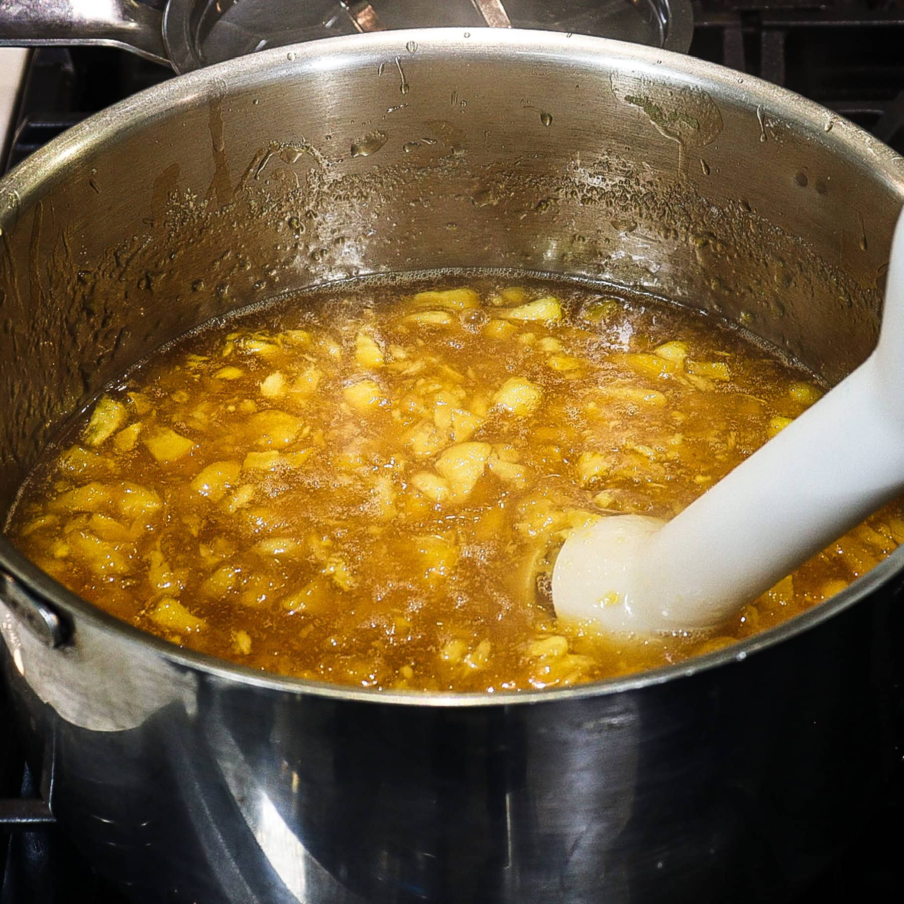 immersion blender breaking down peaches cooking in a pot for peach jam