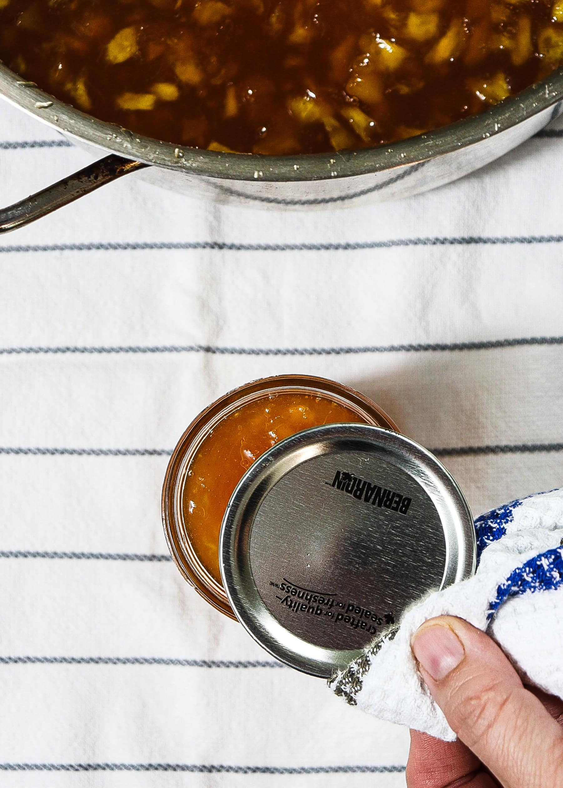 sealing homemade peach and bay leaf jam with a lid