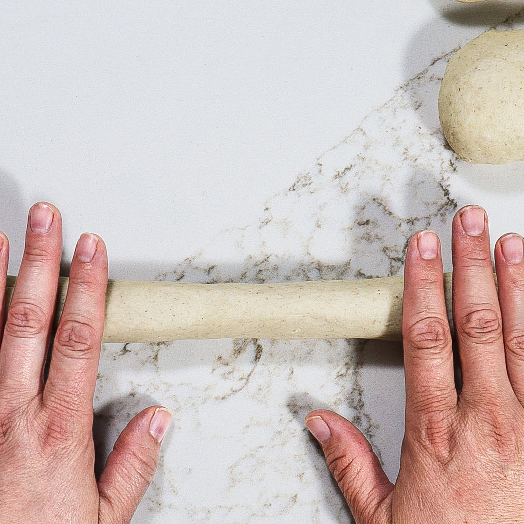 rolling a strand of barley bread dough for braiding