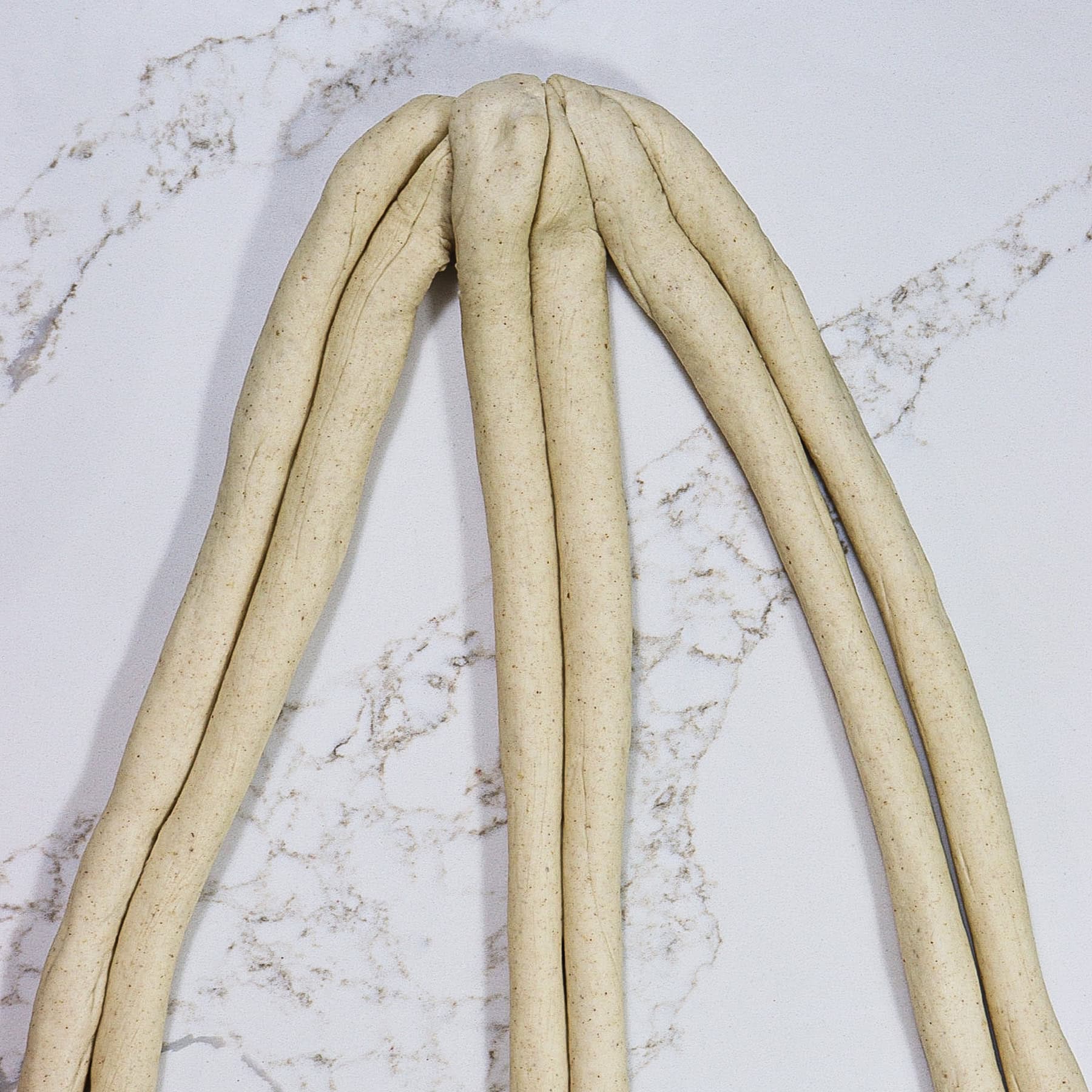 three double ropes of barley bread dough showing first step of braiding the dough
