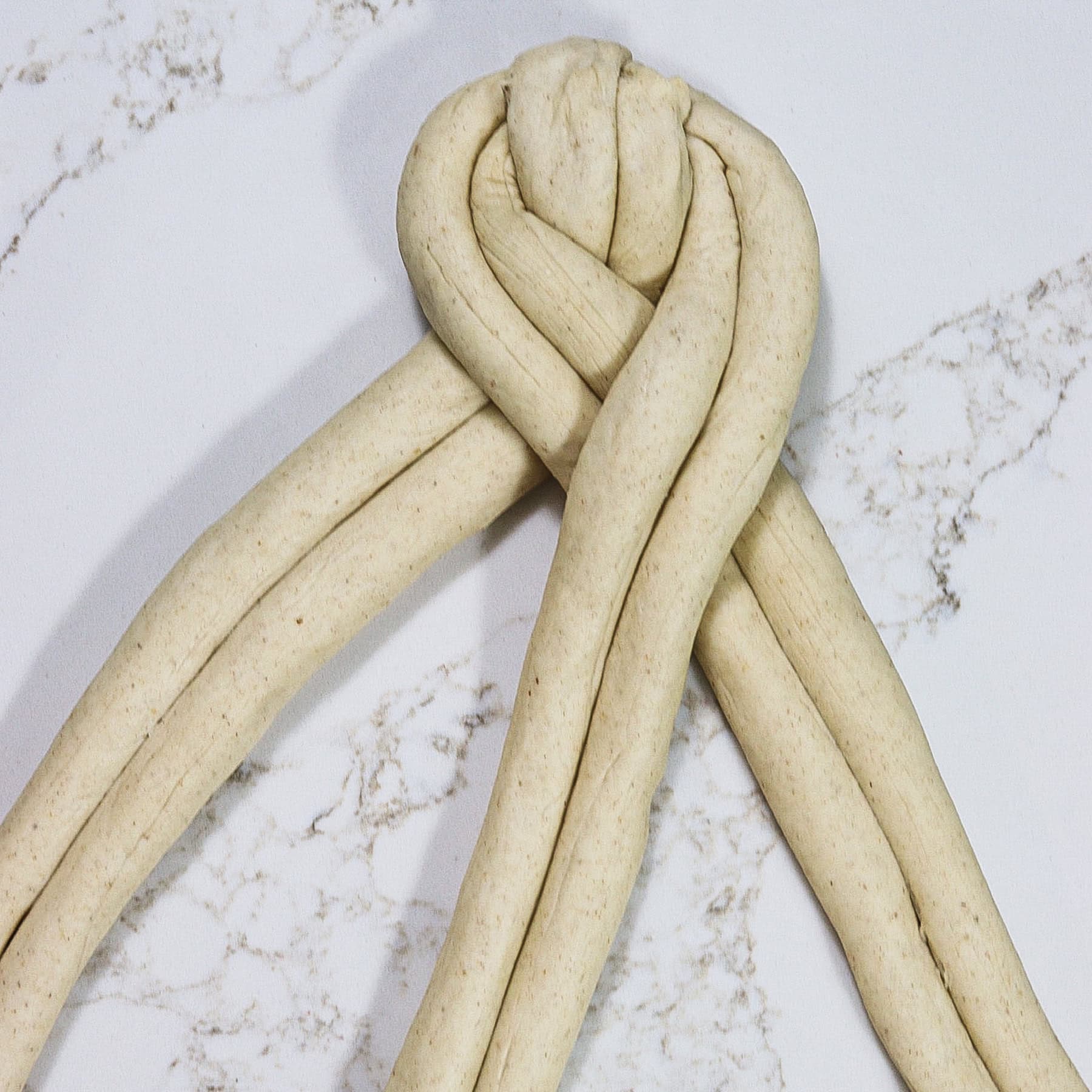 Braiding three double strand ropes of soft barley bread dough