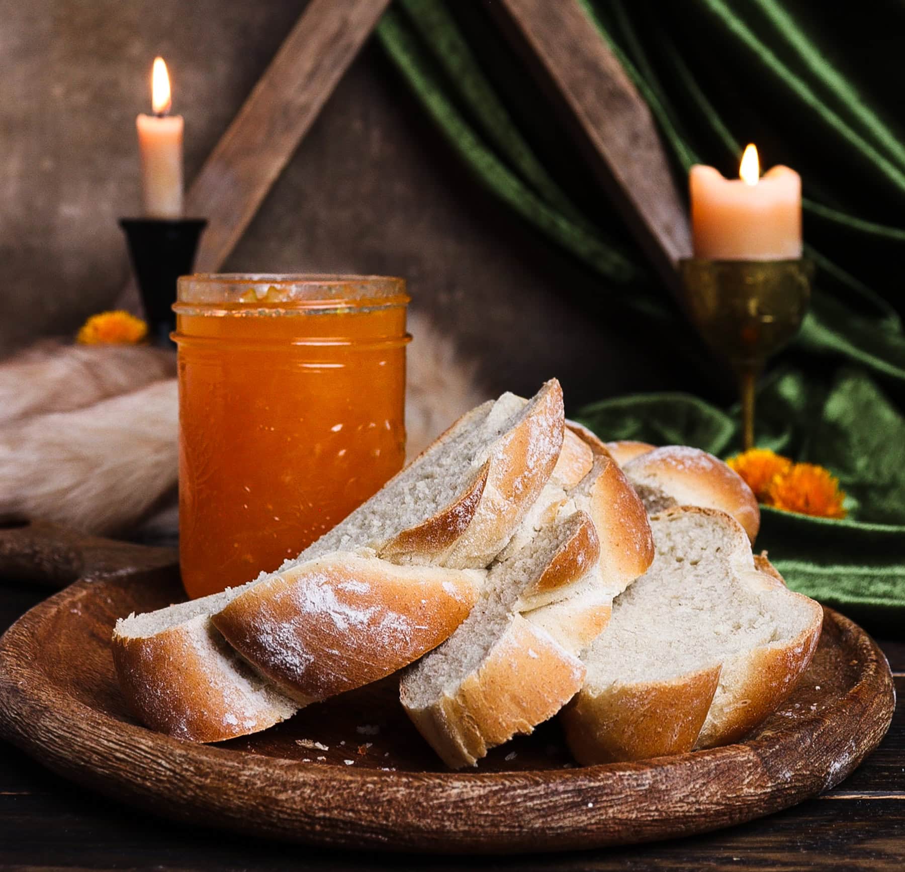slices of soft barley bread on a rustic board with a jar of peach and bay leaf jam