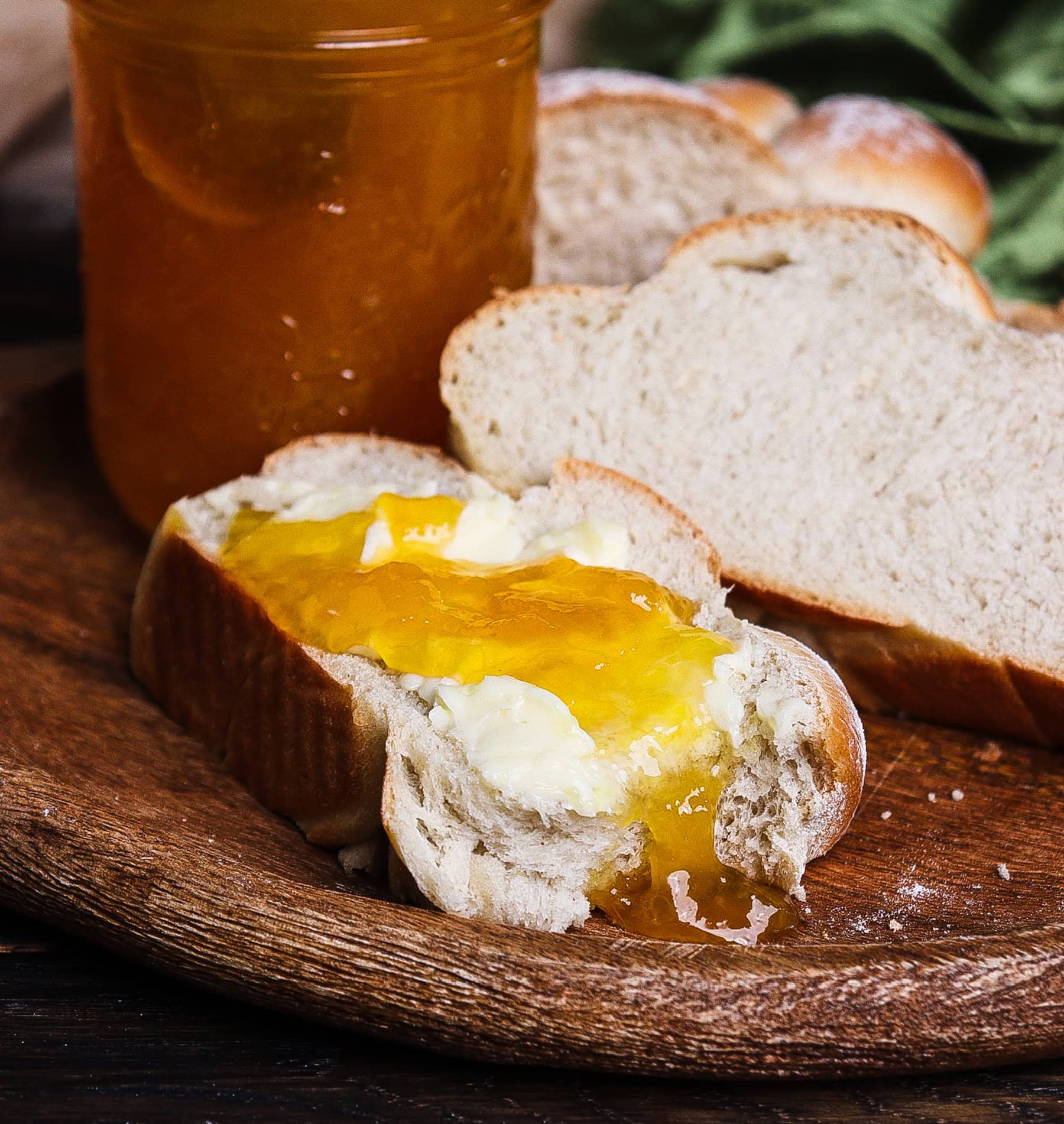 Slice of soft barley bread topped with peach jam and a bite taken out