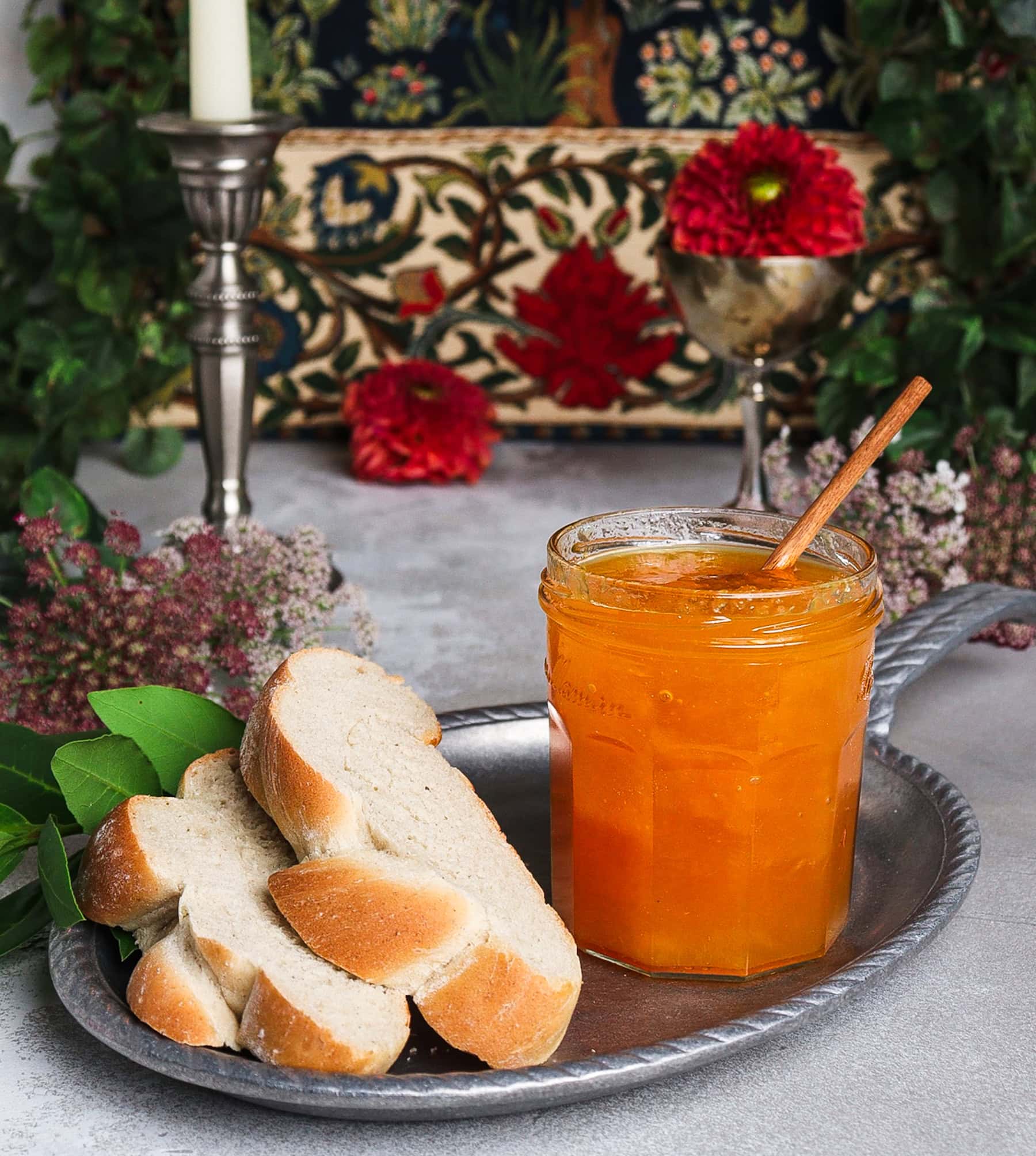 Open jar of peach and bay leaf jam with slices of white bread in a setting inspired by Gondor