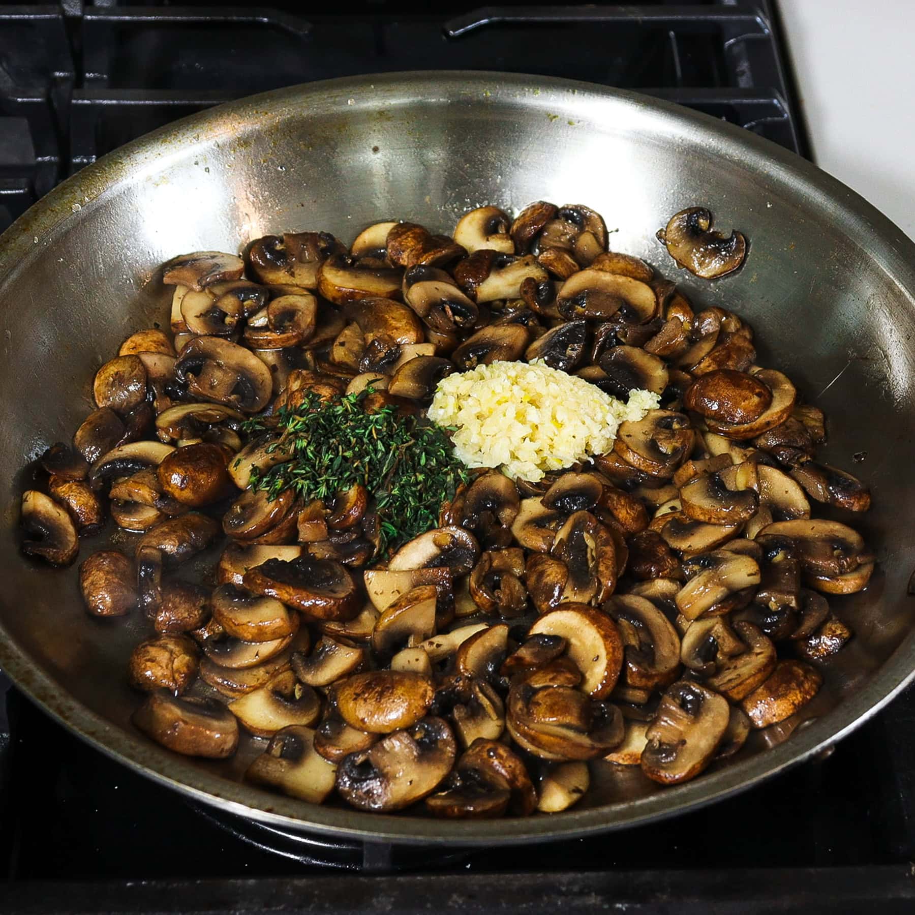 mushrooms sautéing with thyme and garlic on a skillet