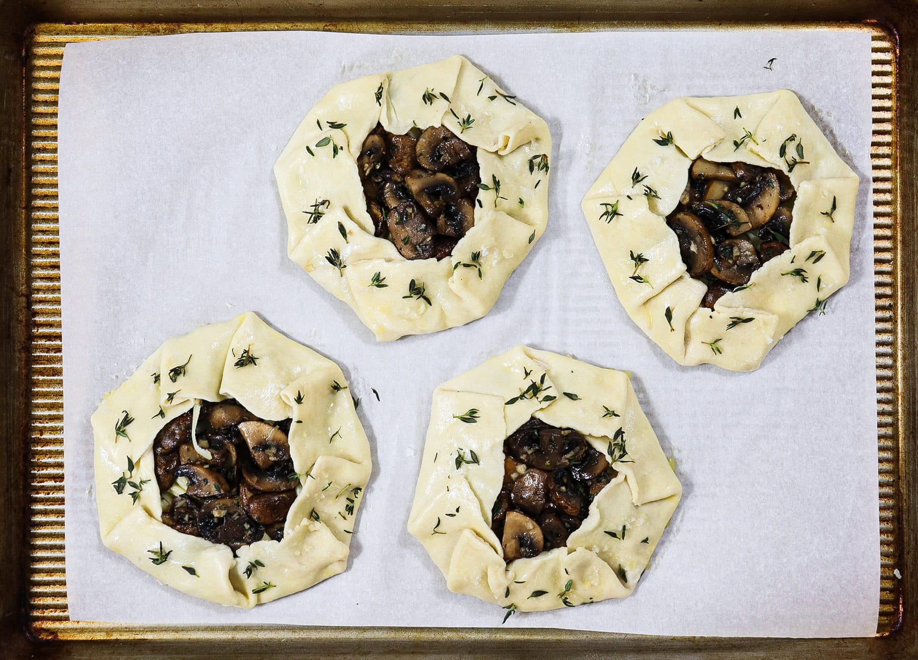4 mini mushroom galettes on a sheet pan ready to bake