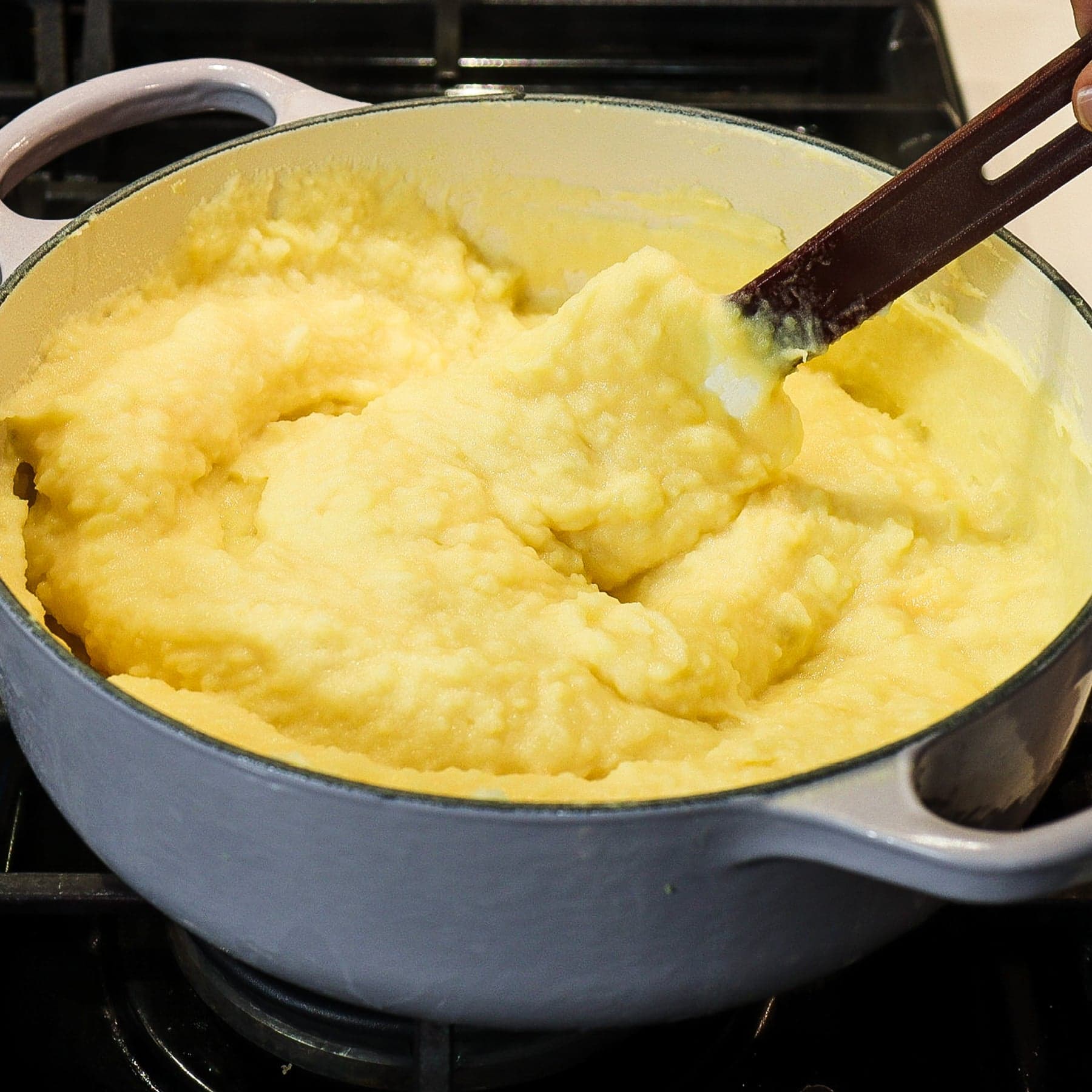 pot of mashed potatoes and cheddar cheese mixed with a spatula 