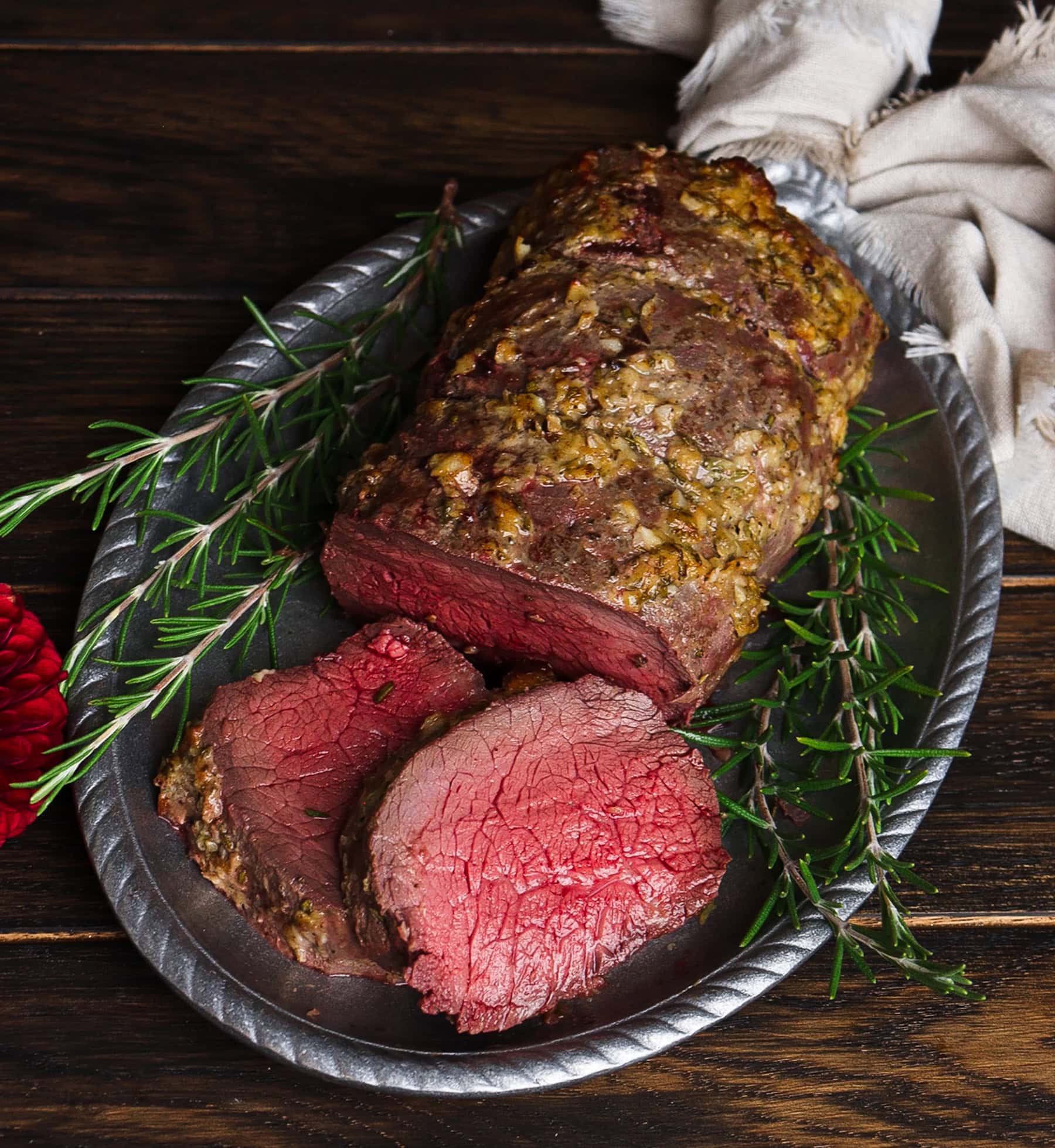 cuts of beef tenderloin with rosemary sprigs on a silver platter