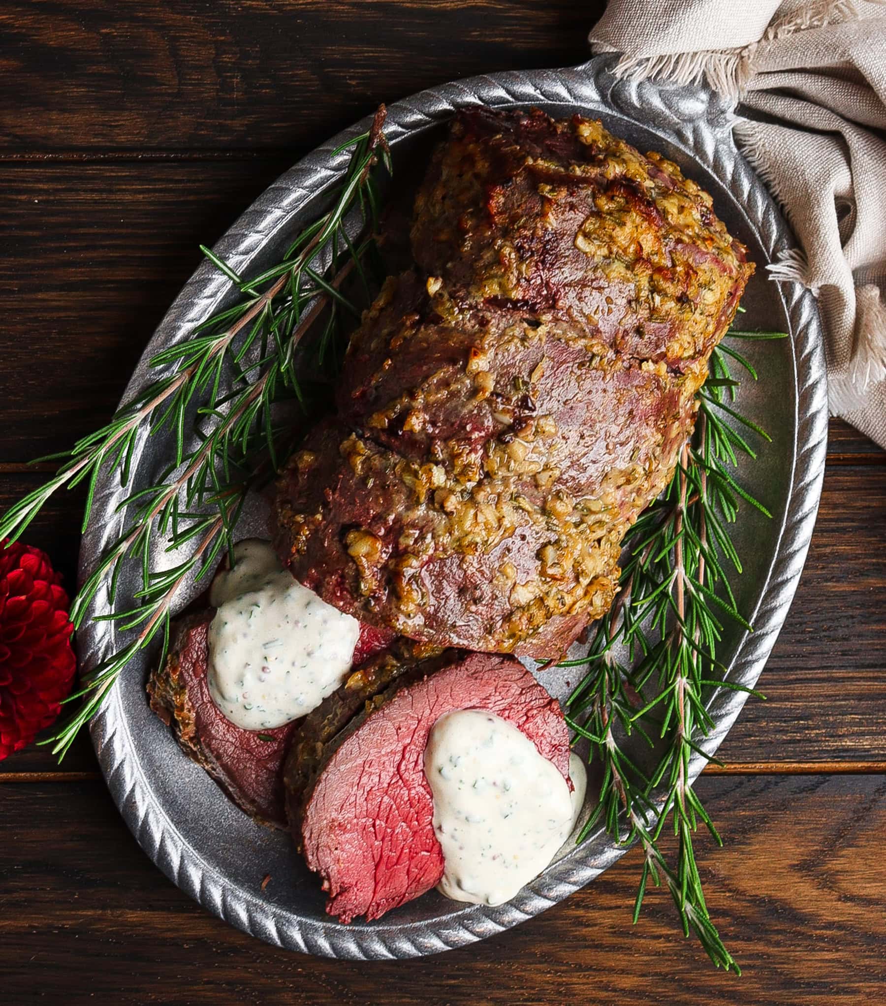 horseradish crusted beef tenderloin topped with creamy mustard sauce on a silver platter