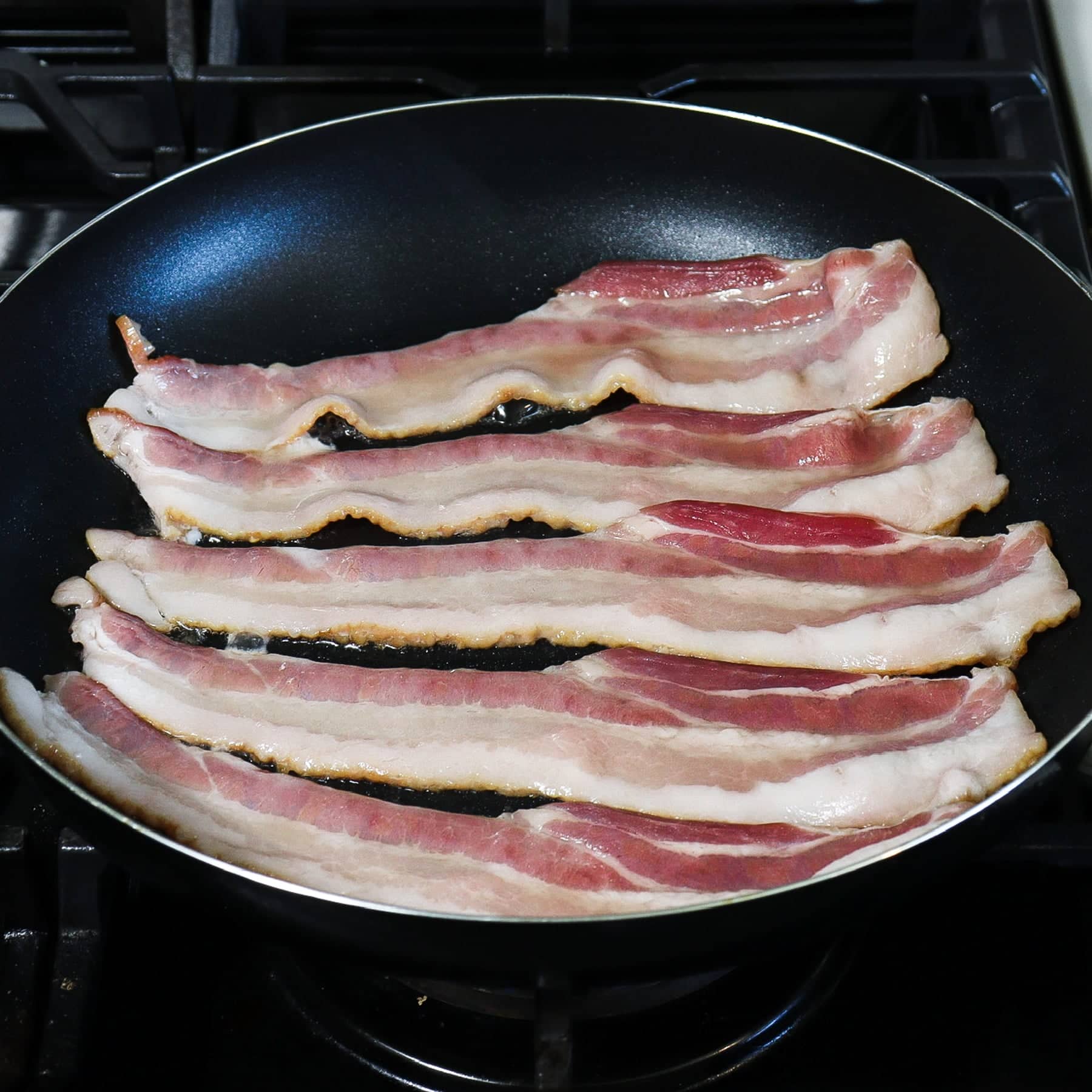 strips of bacon cooking on a skillet