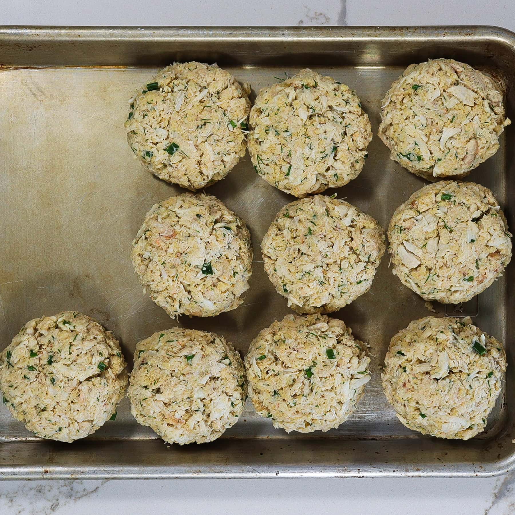 uncooked crab cakes on a sheet pan chilling before frying
