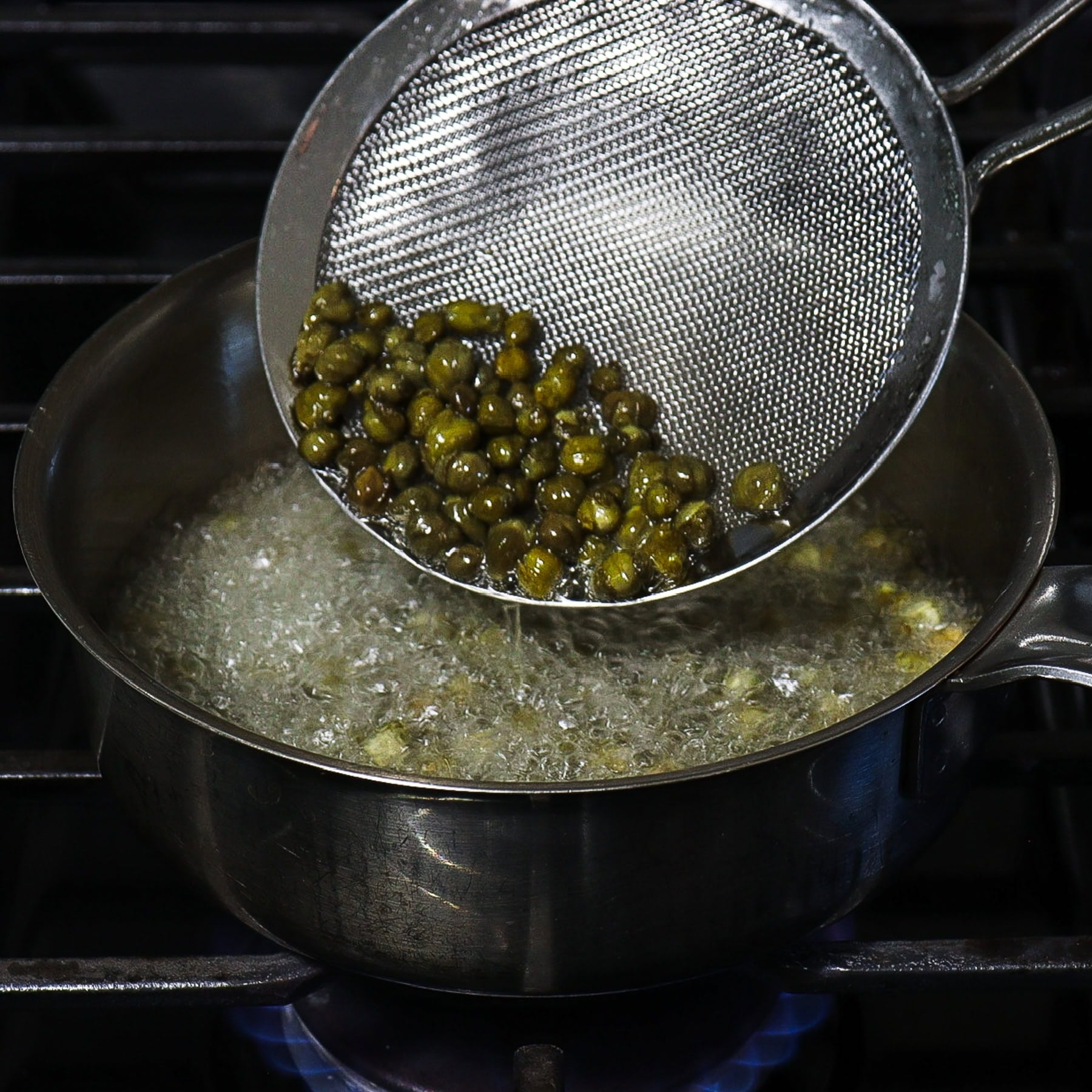 capers frying in oil on a stovetop