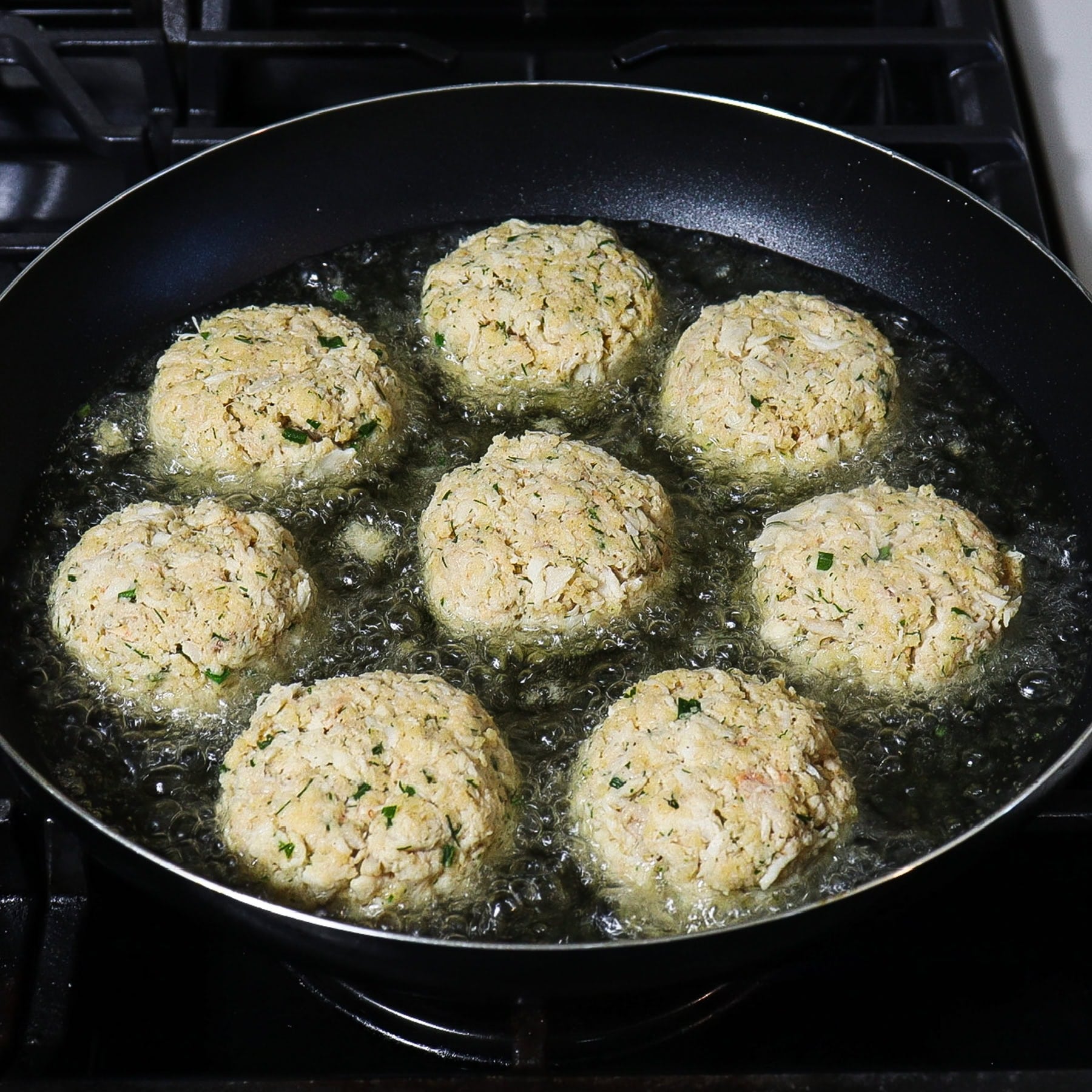 crab crakes frying in oil on a stovetop